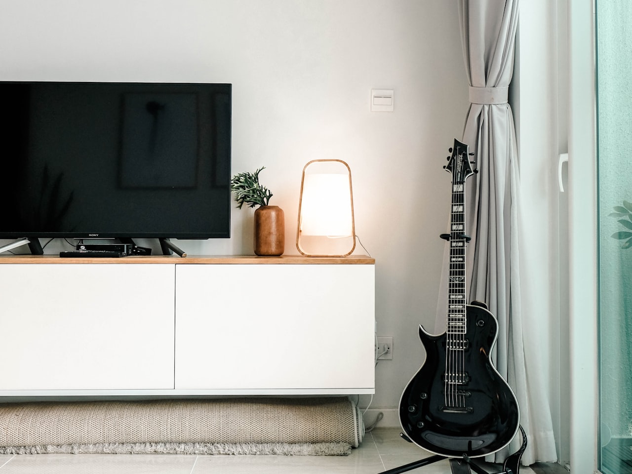 Modern flat-screen smart television on a wooden media unit in a bright living room